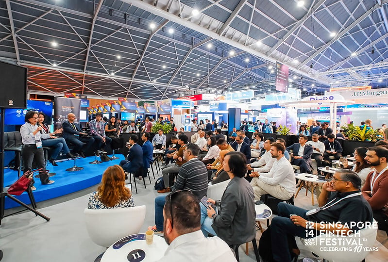 A seated audience listening to a talk on a small stage in the exhibition hall at SFF 2025
