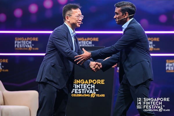 Two speakers shaking hands on the Singapore FinTech Festival stage