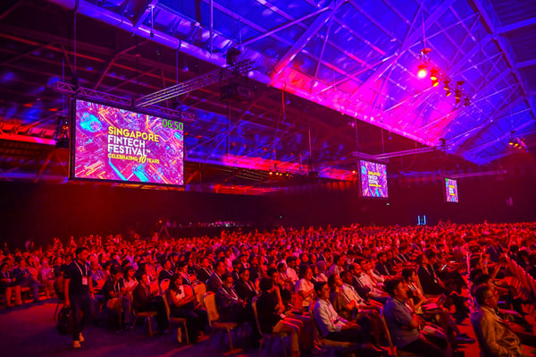 A full plenary hall under red and purple stage lights