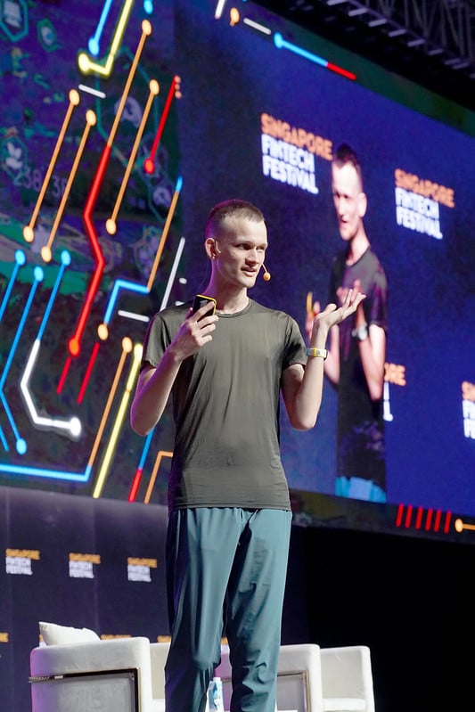 A speaker on stage in front of a large screen