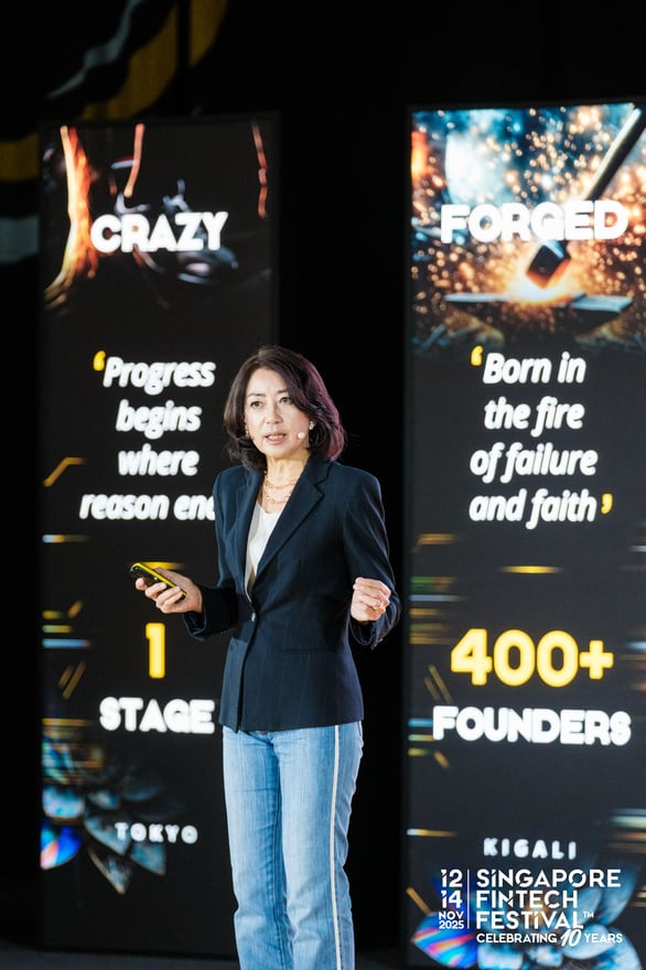 A speaker on stage beside screens reading 400+ founders