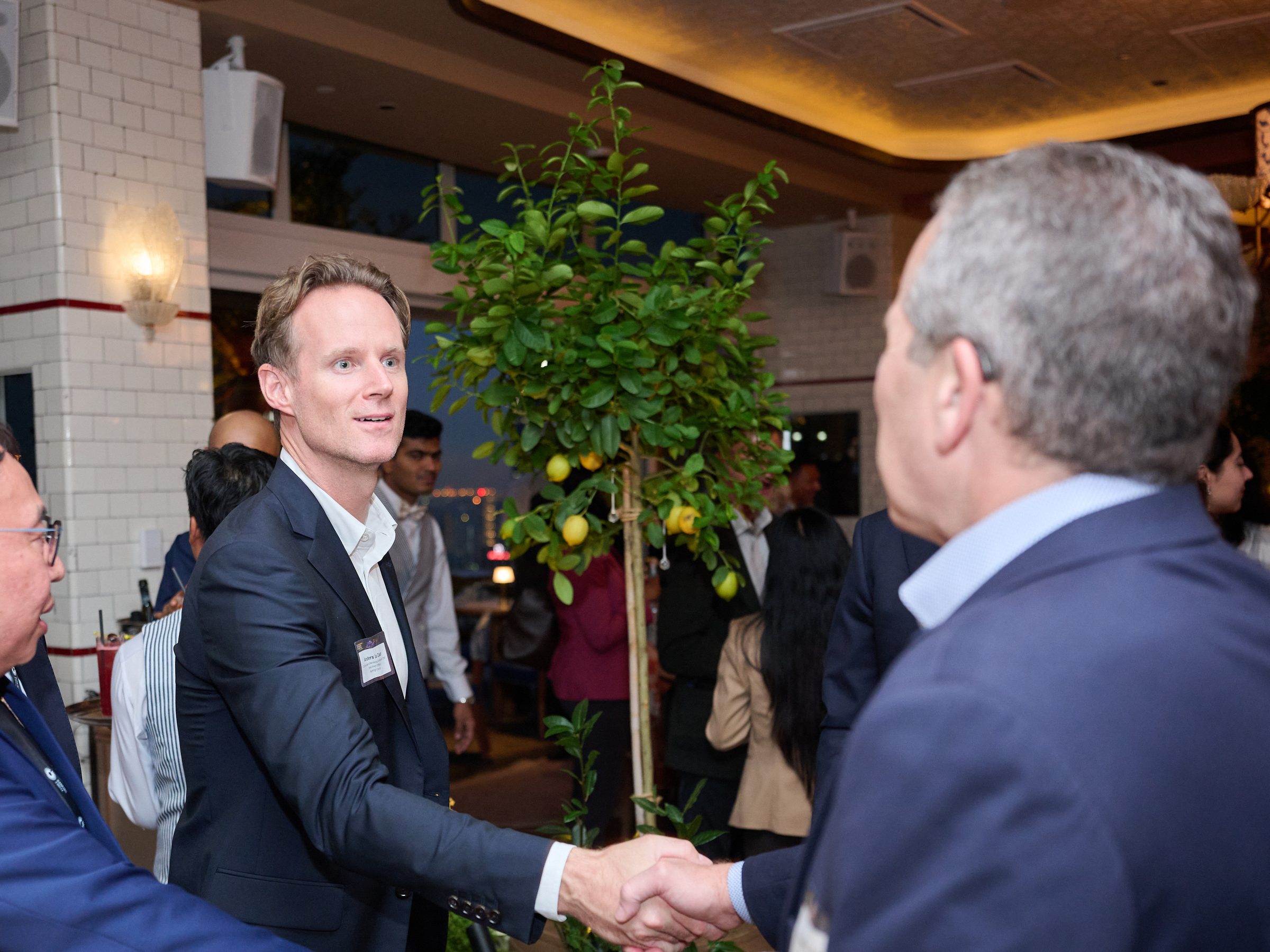 Two delegates shake hands at an evening reception
