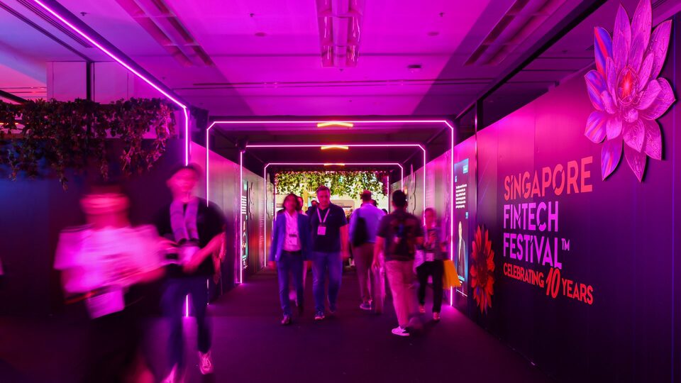 Attendees walk through a neon pink tunnel entrance with Singapore FinTech Festival branding
