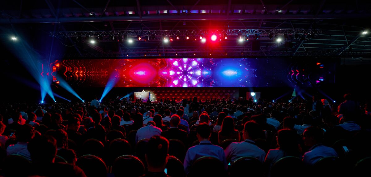 Packed plenary hall facing the lit Festival Stage